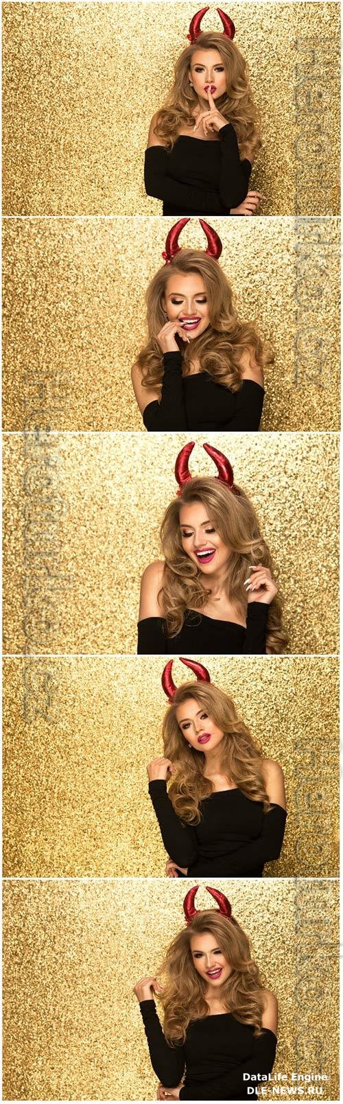 Girl with red horns on gold background stock photo